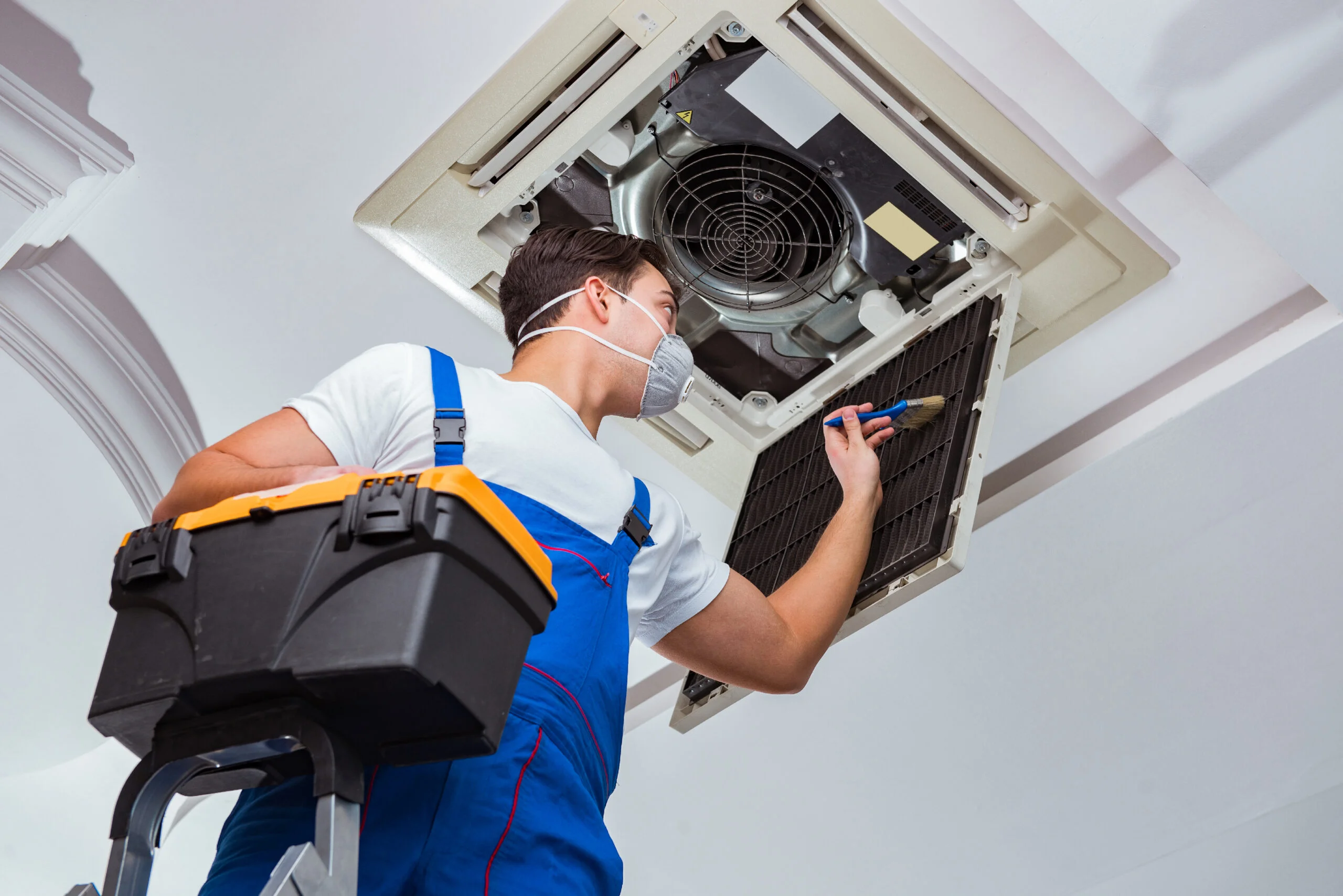 HVAC technician repairing ceiling AC unit in Dubai home