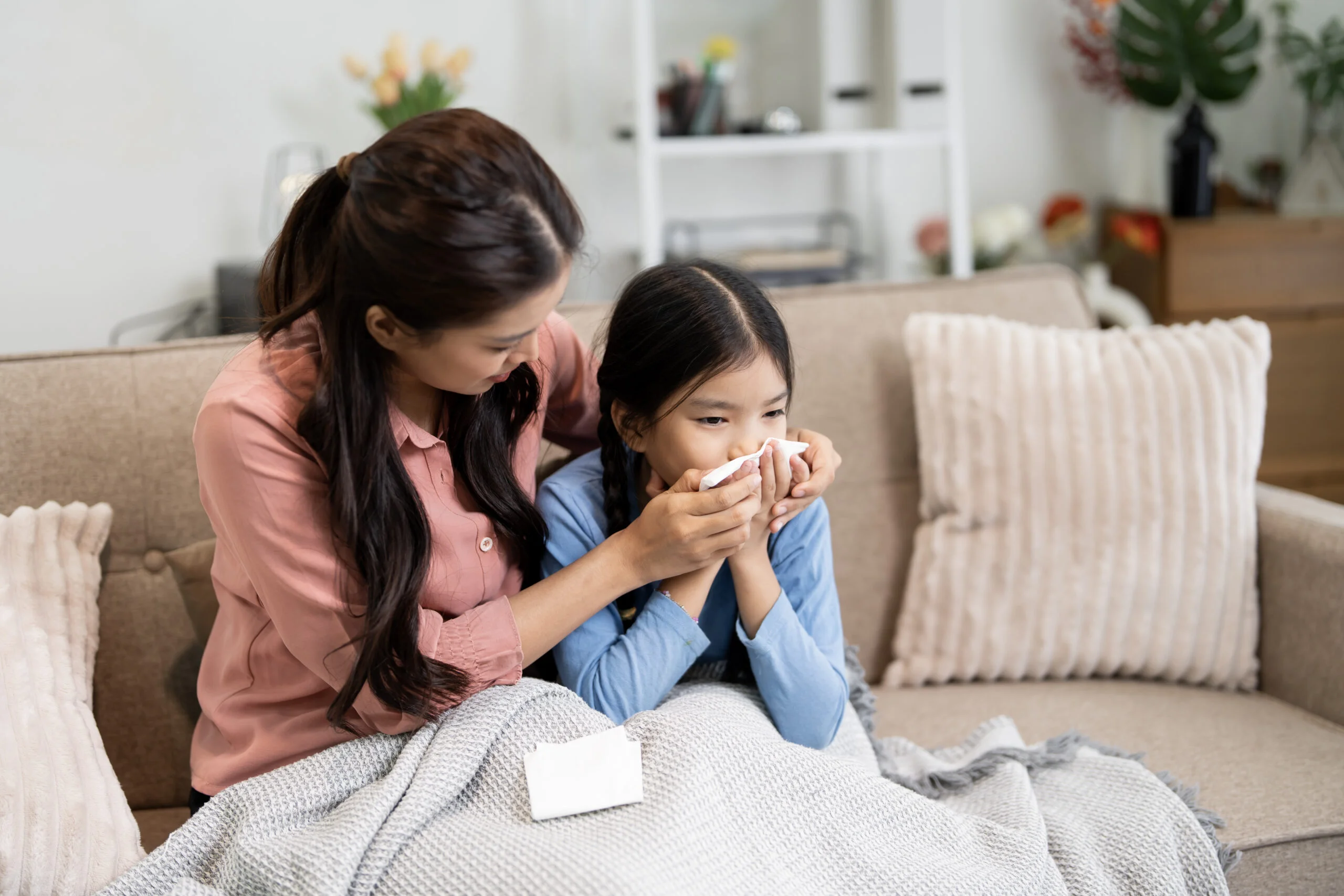 A parent comforting a child sneezing near an AC vent in a UAE home, showing how indoor allergens from AC ducts worsen summer allergies and asthma